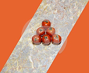 Triangular red cherry tomato on a sloping marble strip