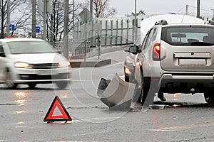 Triangular red retro-reflective sign of accident on the road. Collision of two cars. Broken bumper and hood. Car accident on the