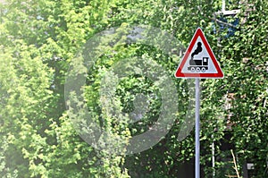 Triangular road sign with a picture of a black locomotive on a white background in a red frame. Warning sign for the presence of