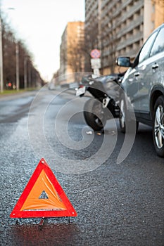 Triangular safety reflector is on asphalt road, sign is on the distance of car and motorcycle crash