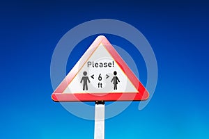 Triangular traffic sign to indicate social distancing and stay alert