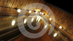 A triangular wooden house decorated with light bulbs in the evening.