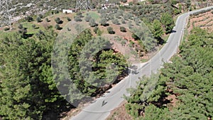 Triathlete is climbing to mountain pass on road bicycle on empty car road, pedaling out of saddle. Cycling and sport concept. Cycl