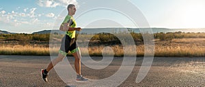 Triathlete in professional gear running early in the morning, preparing for a marathon, dedication to sport and