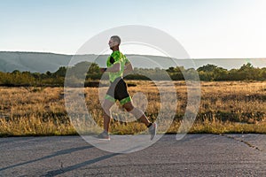 Triathlete in professional gear running early in the morning, preparing for a marathon, dedication to sport and