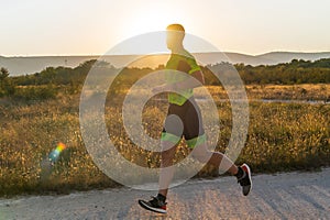 Triathlete in professional gear running early in the morning, preparing for a marathon, dedication to sport and