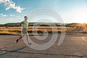 Triathlete in professional gear running early in the morning, preparing for a marathon, dedication to sport and