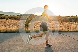 Triathlete in professional gear running early in the morning, preparing for a marathon, dedication to sport and