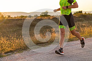 Triathlete in professional gear running early in the morning, preparing for a marathon, dedication to sport and