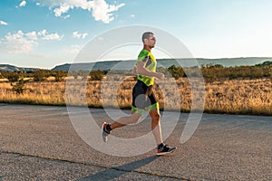 Triathlete in professional gear running early in the morning, preparing for a marathon, dedication to sport and