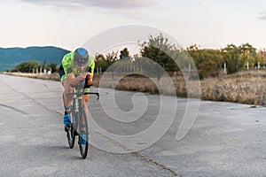 Triathlete riding his bicycle during sunset, preparing for a marathon. The warm colors of the sky provide a beautiful