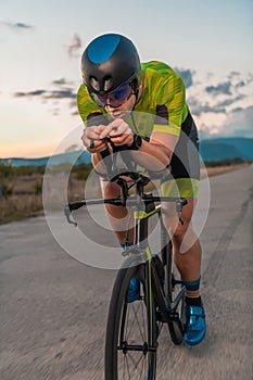 Triathlete riding his bicycle during sunset, preparing for a marathon. The warm colors of the sky provide a beautiful