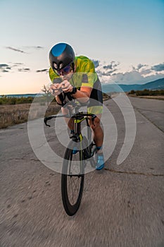 Triathlete riding his bicycle during sunset, preparing for a marathon. The warm colors of the sky provide a beautiful