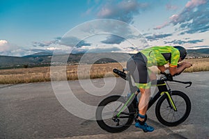 Triathlete riding his bicycle during sunset, preparing for a marathon. The warm colors of the sky provide a beautiful