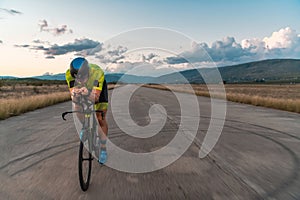 Triathlete riding his bicycle during sunset, preparing for a marathon. The warm colors of the sky provide a beautiful