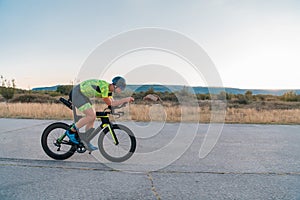 Triathlete riding his bicycle during sunset, preparing for a marathon. The warm colors of the sky provide a beautiful