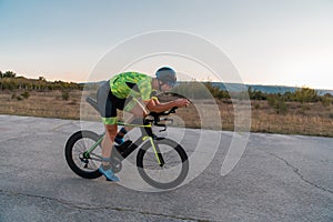 Triathlete riding his bicycle during sunset, preparing for a marathon. The warm colors of the sky provide a beautiful