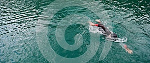 Triathlon athlete swimming on lake wearing wetsuit