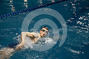 Triathlon athlete trains to swim in the pool . White man swimming in blue water banner panorama. Sports and fitness