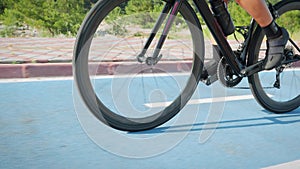 Triathlon and cycling concept. Cyclist riding bicycle on bike path in the morning. Female professional triathlete twists pedals on