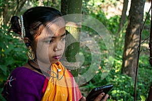 A tribal little girl is listening to music with Bluetooth headphones on her android phone