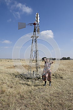 Tribal woman standing next to windpump on farm