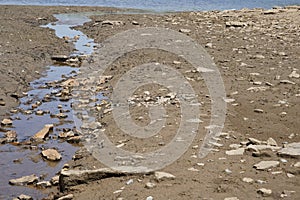 Tributary stream of a lake on the dried up bottom of soil. A sign of water scarcity that diminishes the body of water.