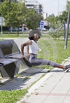 Triceps exercise. On the street. An American or African woman.