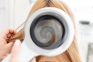 A trichologist examines the condition of the hair on the patient head with a dermatoscope. In a bright cosmetology room