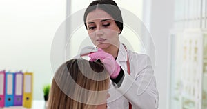 Trichologist examines hair roots using magnifying glass