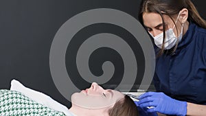 A trichologist performs a skin treatment procedure on a young woman's head. Vitamin injections