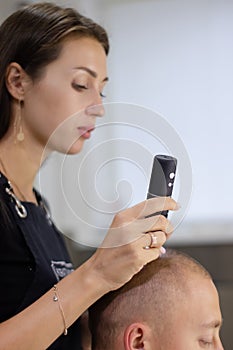 Trichoscope examination of hair, scalp and hair follicles of a young man. Copy space. The head of a man with thinning