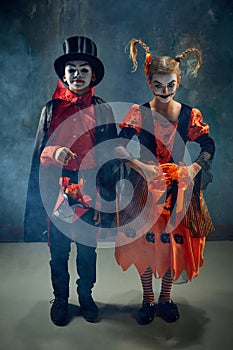 Trick or treat. Boy and girl, children wearing costumes for halloween, standing with basket for candies against dark