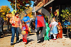 Trick or treaters and their parents enjoy a sunny Halloween day receiving candy in downtown