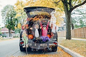 Trick or trunk. Children celebrating Halloween in trunk of car. Boy and girl with red pumpkins celebrating traditional October