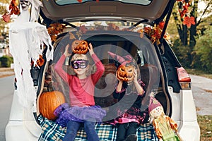 Trick or trunk. Children siblings sisters celebrating Halloween in trunk of car. Friends kids girls preparing for October holiday