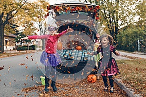 Trick or trunk. Children siblings sisters celebrating Halloween in trunk of car. Friends kids girls preparing for October holiday