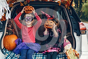 Trick or trunk. Children siblings sisters celebrating Halloween in trunk of car. Friends kids girls preparing for October holiday