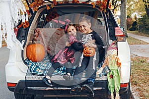 Trick or trunk. Family celebrating Halloween in trunk of car. Mother with three children kids celebrating traditional October