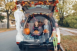 Trick or trunk. Family celebrating Halloween in trunk of car. Mother with three children kids celebrating traditional October