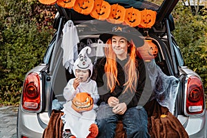 Trick or trunk. Trunk or treat. Happy children in costumes celebrating Halloween party eating candies in decorated trunk of car.