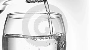 Trickle of water in a super slow motion finishing to serve of the glass bottleneck in a tumbler glas