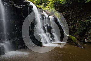 Hidden cascading waterfall in a deep gorge with trickling white water. Forest of Bowland, Ribble Valley, Lancashire