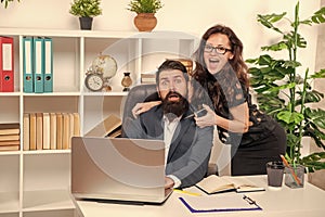 Tricky woman boss scare bearded man employee cutting beard with scissors in office, barbering