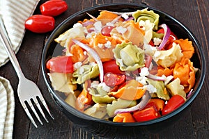 Tricolored tortellini pasta salad on dark wood table