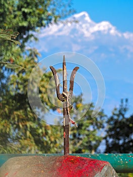 Trident at Kali Temple above stone with vermillion red pigment powder to worship Goddess Kali with mountain background