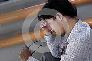Tried stressed young Asian business man takes off glasses. he feeling upset or disappointed with job.
