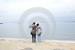 Trieste, September 5 2017, Italy: a couple of tourist taking photos standing on a stone pier