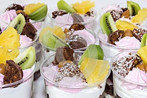 Trifle cake in glass, chocolate biscuit cakes with cream cheese and blueberry jam, decorated with meringue, fruit and candy