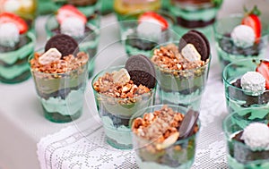 Trifles in plastic glasses with fresh fruit and cream.